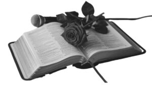 Eine Bibel mit einer Rose sowie einem Mikrofon in schwarz/weiss